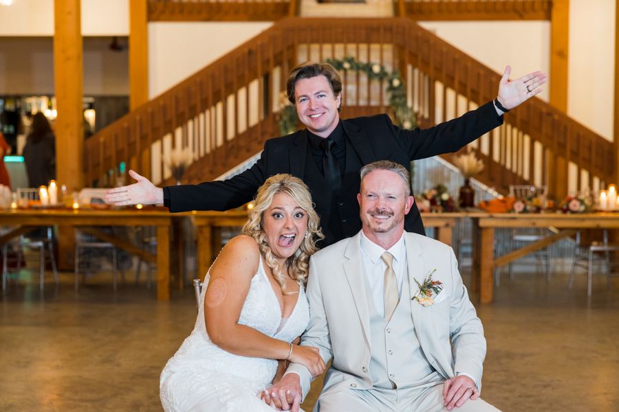 Reed posing playfully behind the newlyweds at the reception